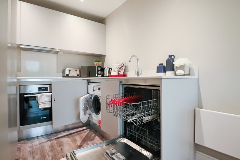 Modern kitchen with white cabinetry, stainless steel appliances, and wooden flooring