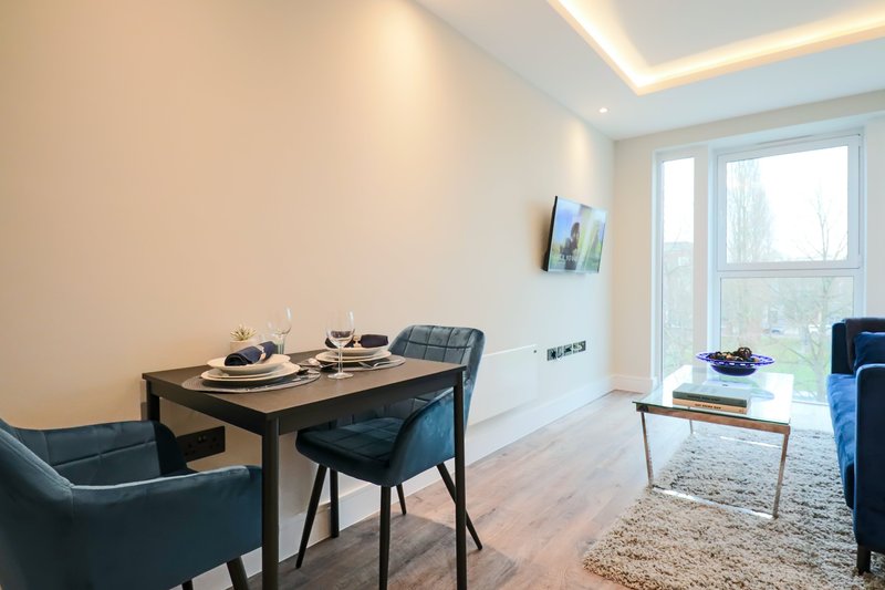 Modern dining area with table, chairs, and living room seating with large windows