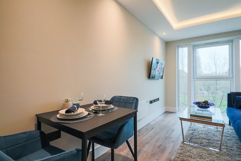 Modern dining area with black table, chairs, place settings, and glass doors overlooking garden