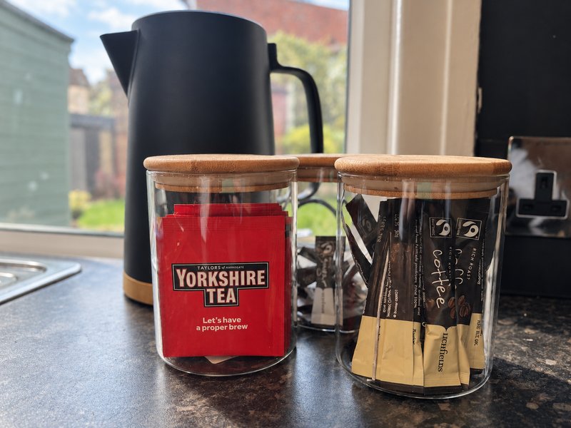 Kitchen counter with black kettle, tea container, and utensil holder by window