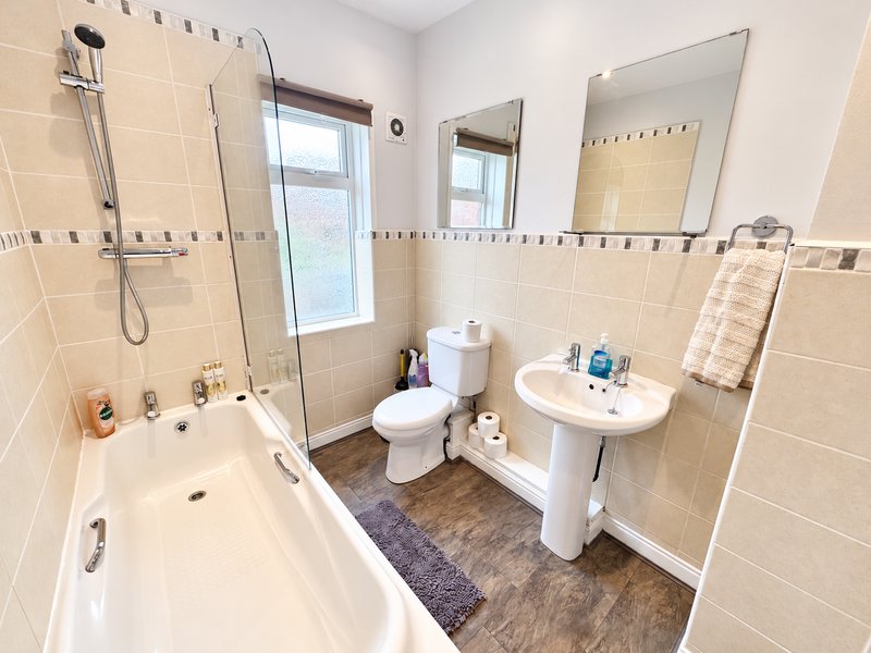 Clean bathroom with bathtub, shower enclosure, pedestal sink, toilet and mirrors