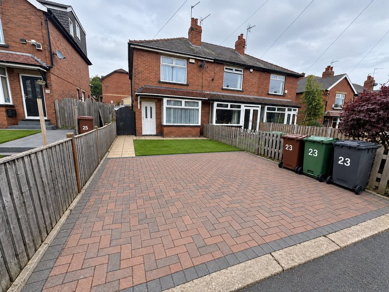 Red brick semi-detached house with driveway, front garden and number 23 displayed