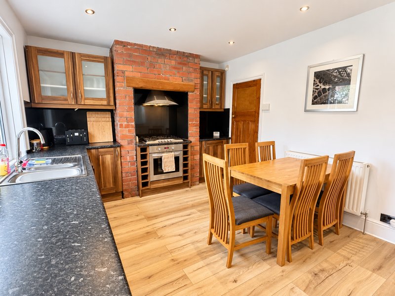 Open-plan kitchen and dining area with wooden table, brick fireplace, and stove