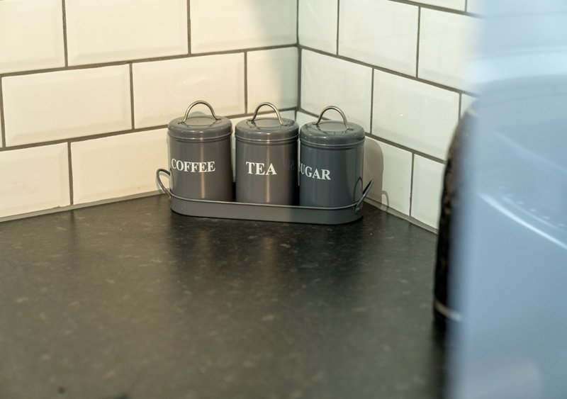 Kitchen counter with three labeled storage canisters for coffee, tea, and sugar