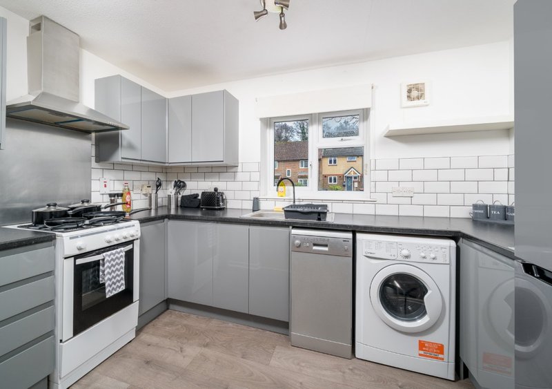 Modern kitchen with grey cabinets, white subway tiles, gas hob, washing machine and dishwasher