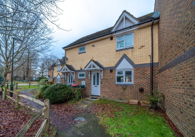 Brick semi-detached house with front garden, driveway and bare trees