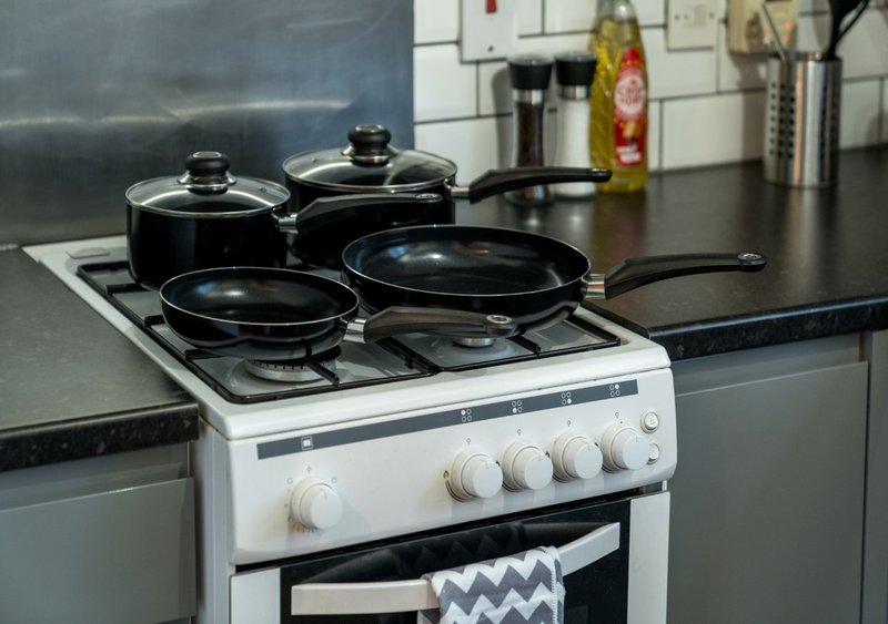 Kitchen stovetop with cookware, white range cooker and black countertop