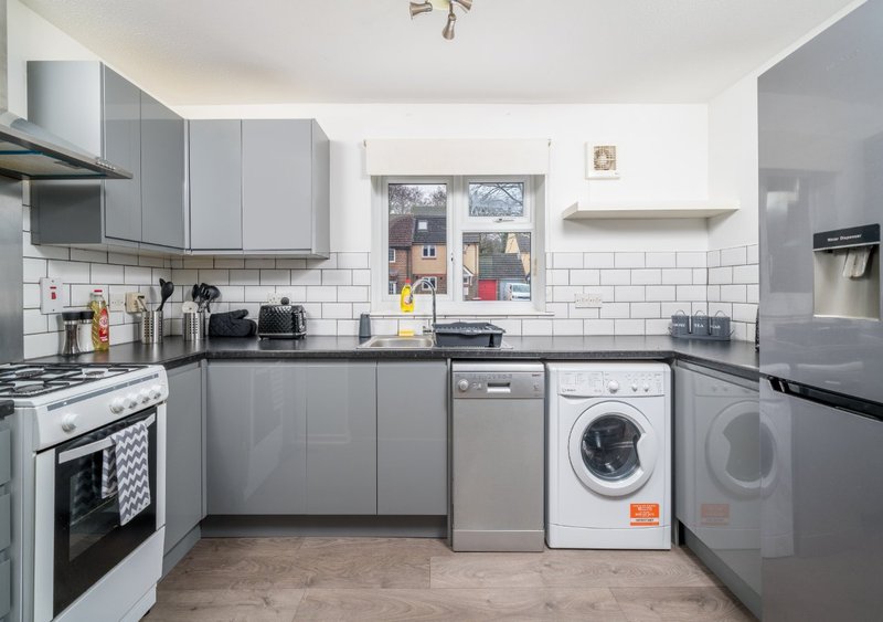 Modern kitchen with gray cabinetry, white subway tile backsplash, integrated appliances and washing machine