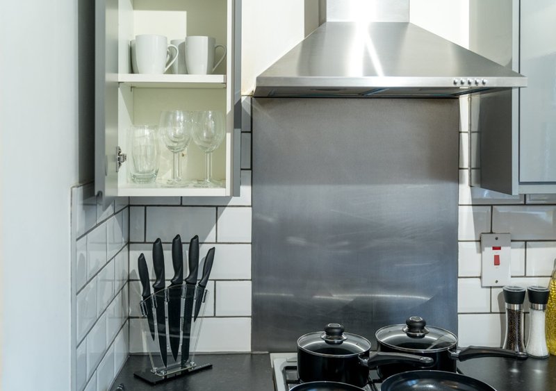 Modern kitchen with stainless steel cooker hood, black stovetop, and white subway tile splashback