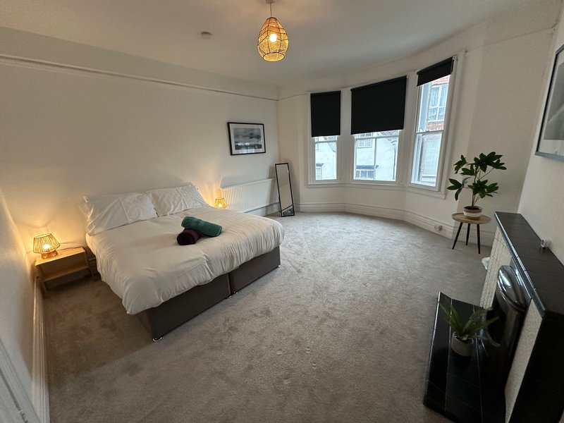 Spacious bedroom with double bed, pendant lighting, bay windows, and modern furnishings