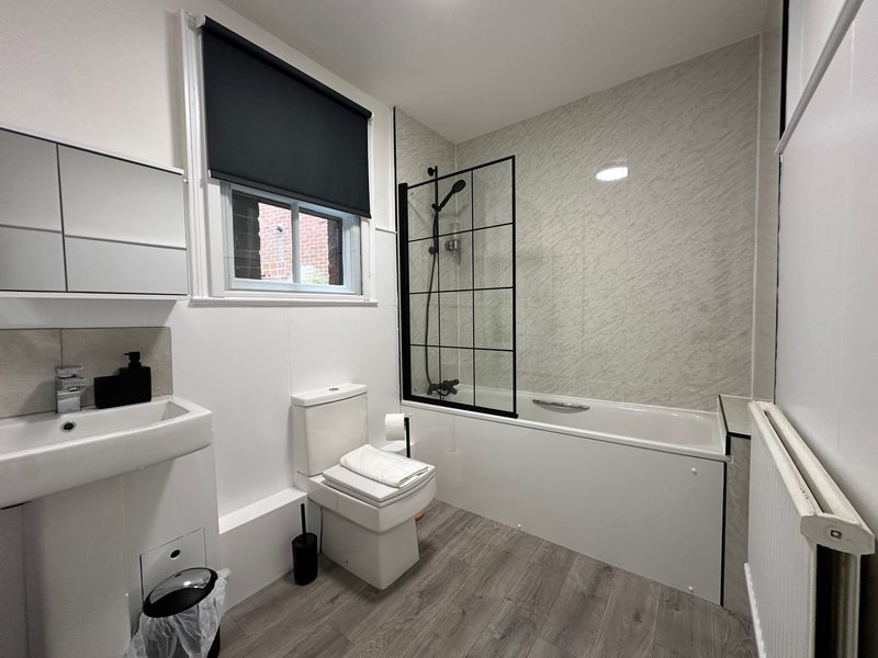 Modern bathroom with white sink, toilet, shower enclosure and window