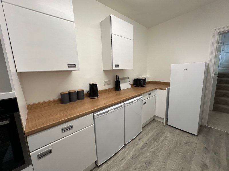 Modern kitchen with white cabinets, wooden countertop, white appliances and storage containers