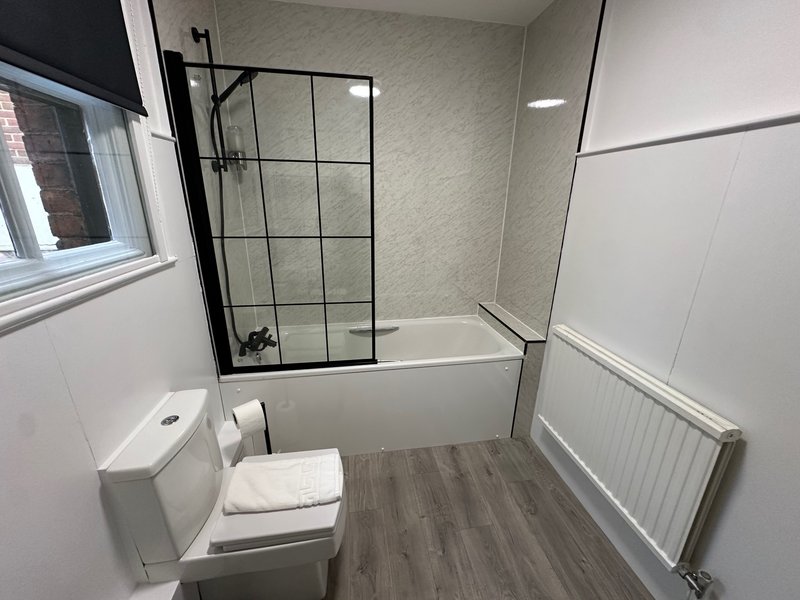 Modern bathroom with toilet, bathtub, glass shower enclosure and heated towel rail
