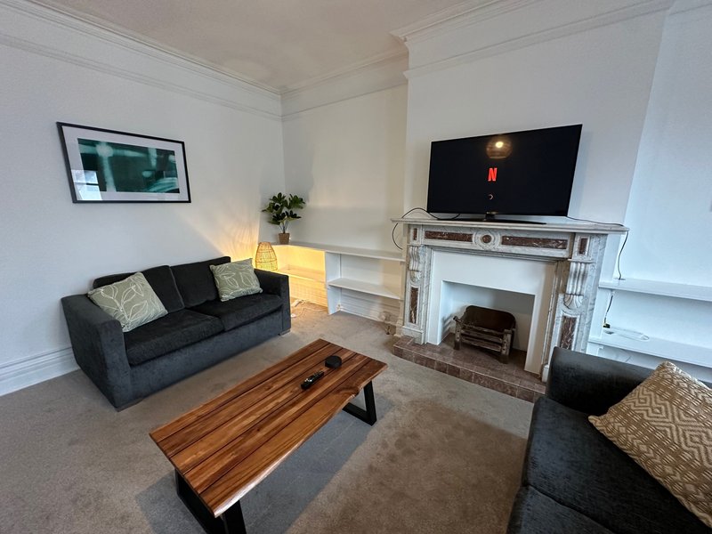 Bright living room with dark sofa, wooden coffee table, fireplace and wall-mounted TV
