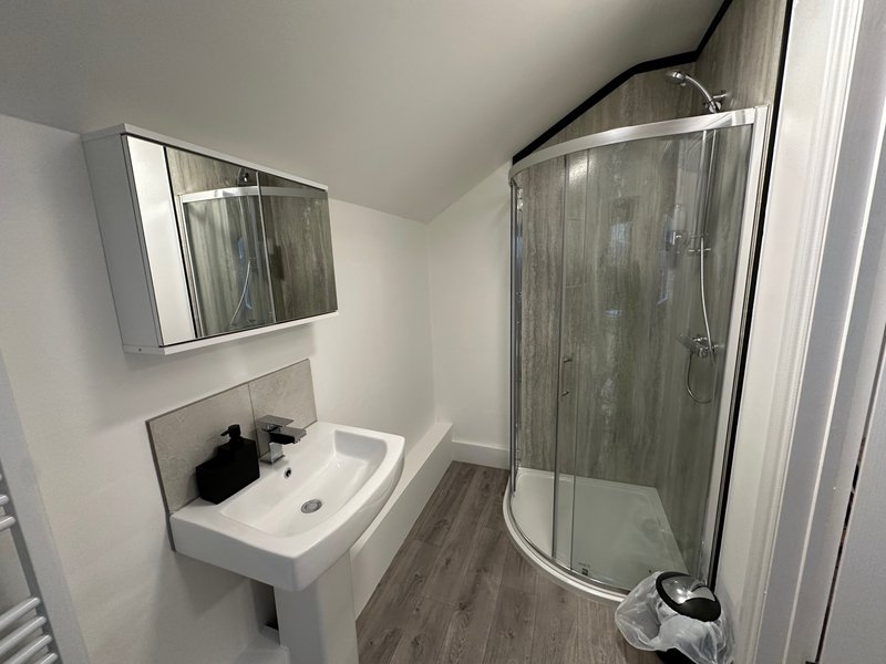 Modern bathroom with white sink, mirror cabinet, and glass shower enclosure