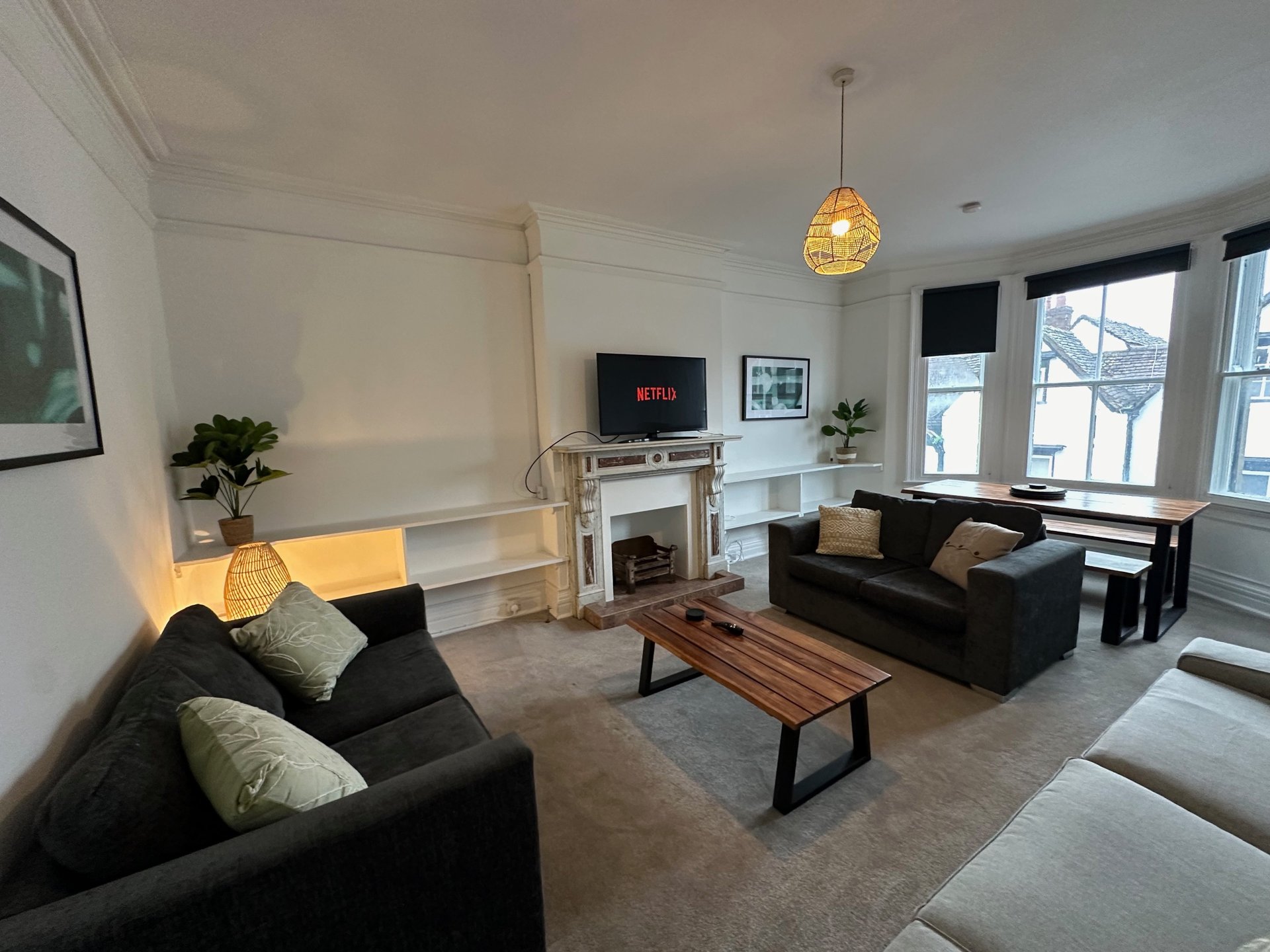 Modern living room with black sofas, fireplace, TV, wooden table and pendant lighting
