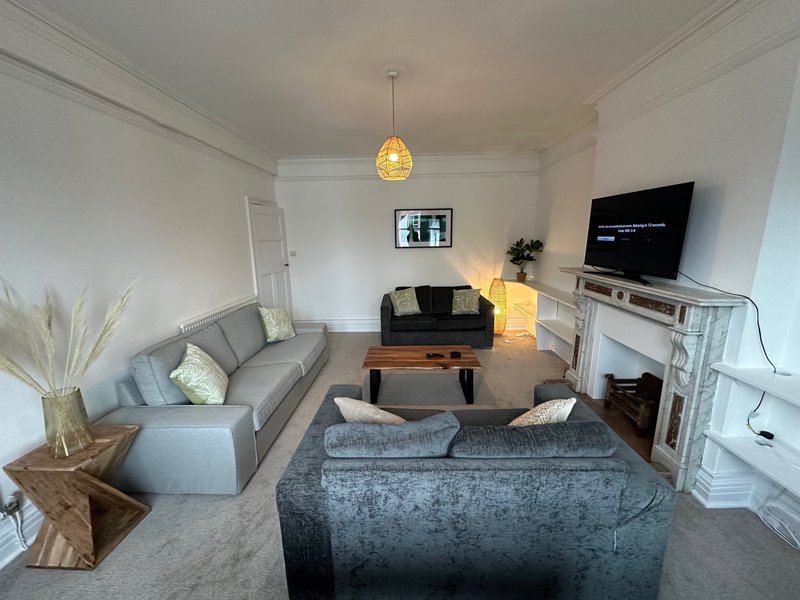 Bright living room with gray sofa, wooden table, TV, fireplace and pendant lighting