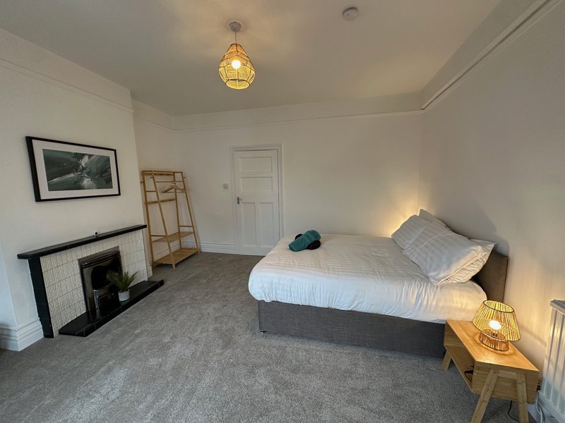 Spacious bedroom with double bed, fireplace, wooden ladder, and pendant lighting