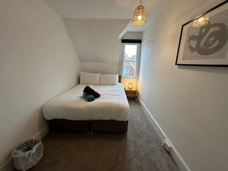 Compact bedroom with single bed, pendant lighting, window, and framed wall art