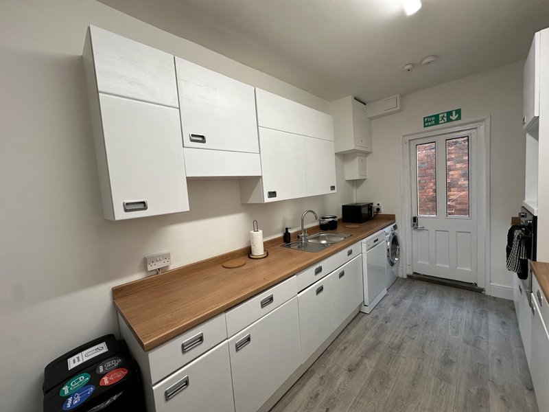 Modern kitchen with white cabinets, wooden countertop, white appliances and brick exterior view