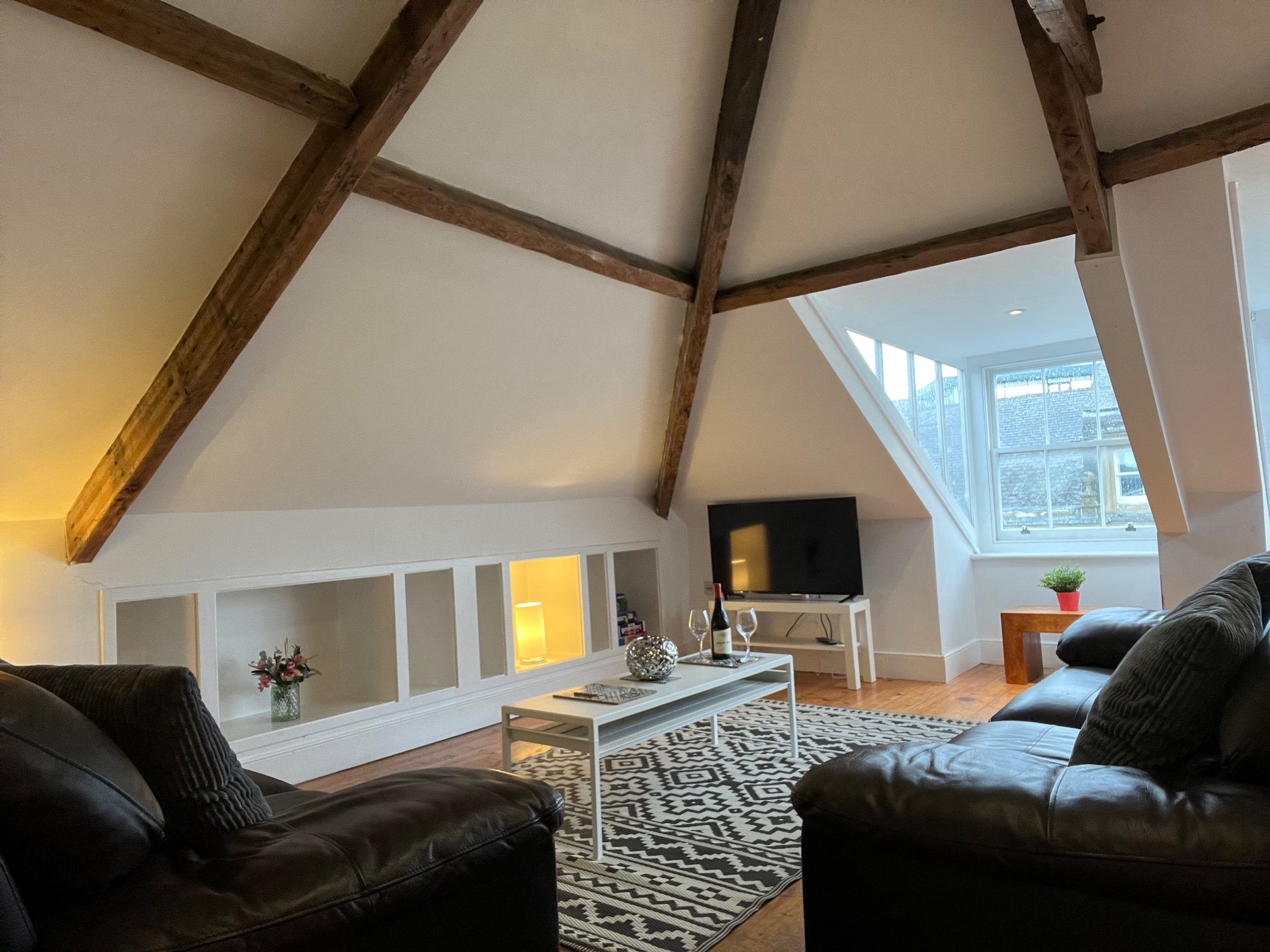 Spacious loft living room with exposed beams, leather sofas, and skylights