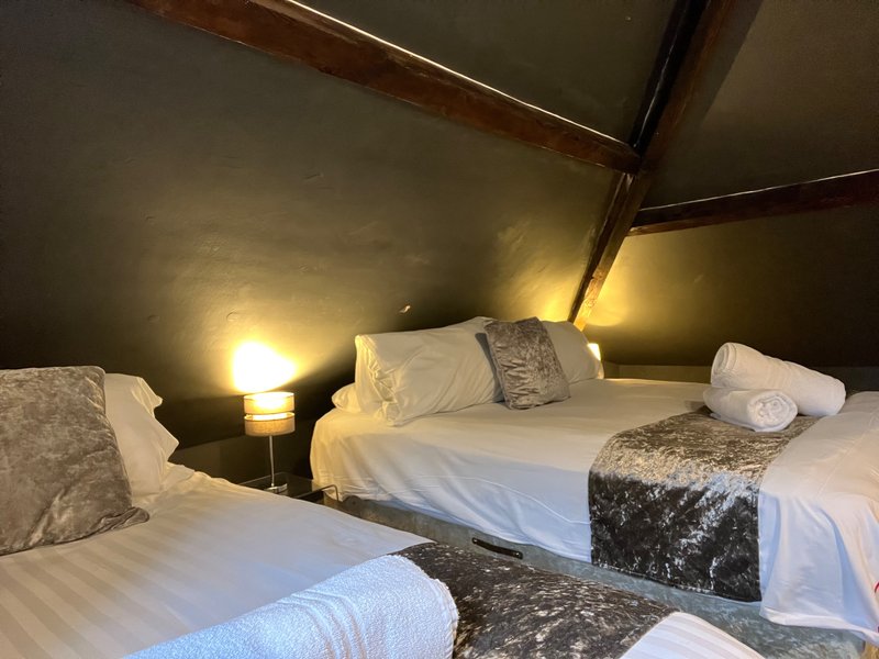 Twin bedroom with two beds, white linens, decorative cushions, bedside lamps, and sloped ceiling