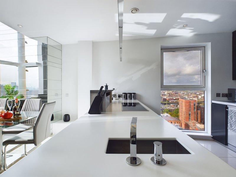 Modern kitchen with white countertop, integrated sink, and panoramic city view through large window