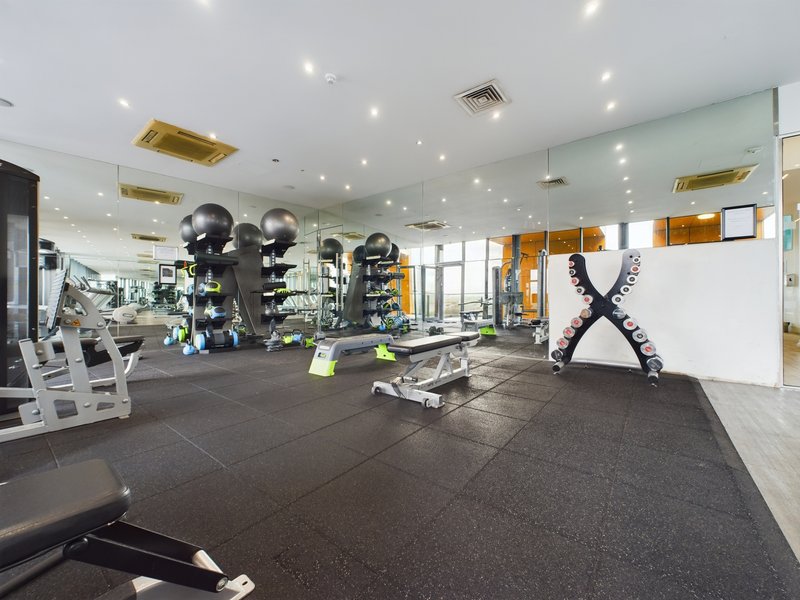 Modern gym interior with exercise equipment, dumbbells, mirrors and bright lighting