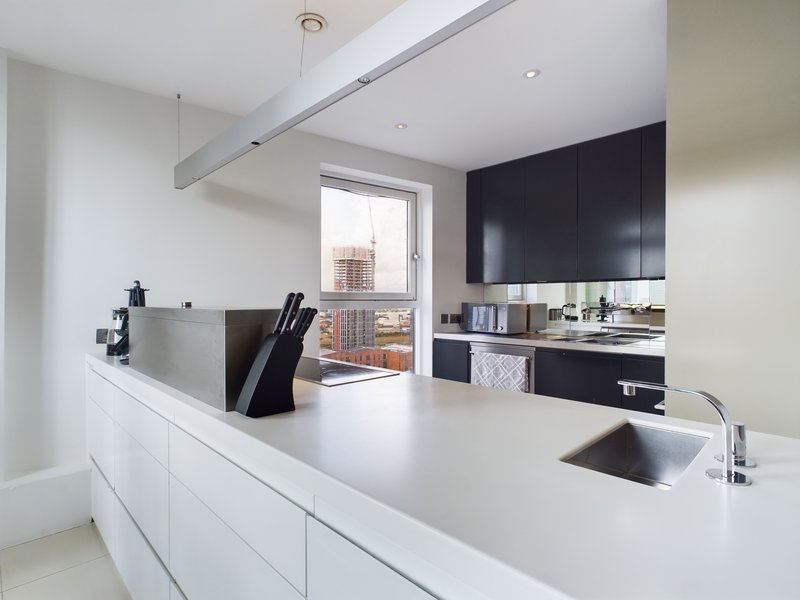 Modern kitchen with white island, black cabinetry, stainless steel sink and city view