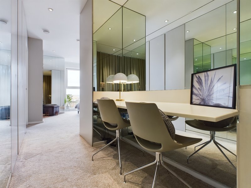 Modern office workspace with desk, chairs, monitor, and mirrored walls with green accents