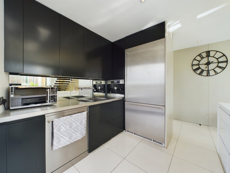 Modern kitchen with black cabinetry, stainless steel appliances, and wall clock