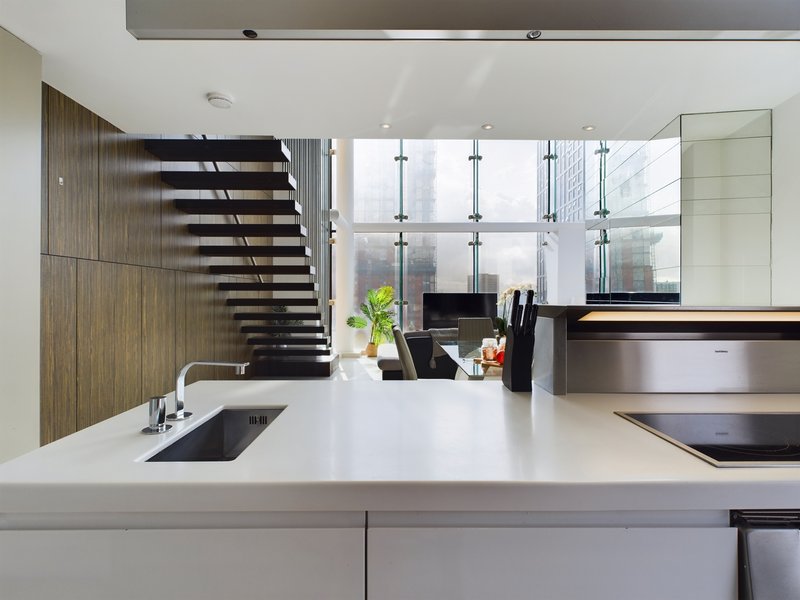 Modern kitchen with white countertop, stainless steel appliances, and city skyline views through large windows