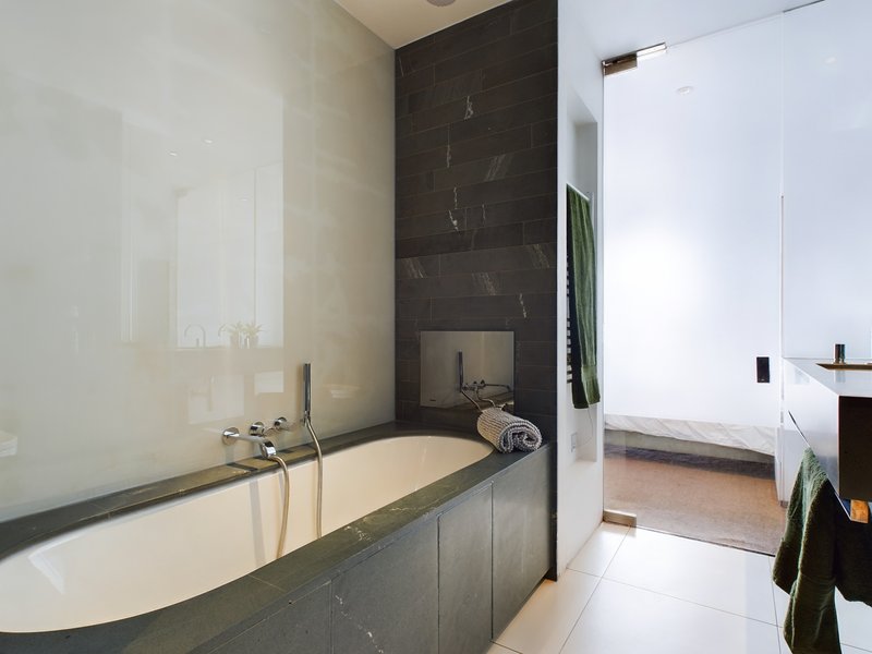 Modern bathroom with sunken bathtub, dark tile surround, and contemporary fixtures