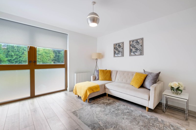 Bright living room with cream sofa, yellow throw, wooden-framed windows and pendant light