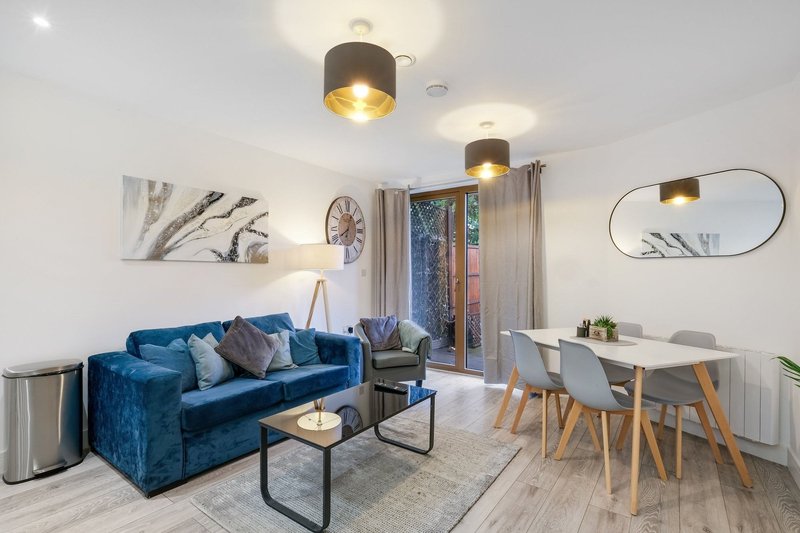 Modern living room with blue velvet sofa, dining table, pendant lights and wall art