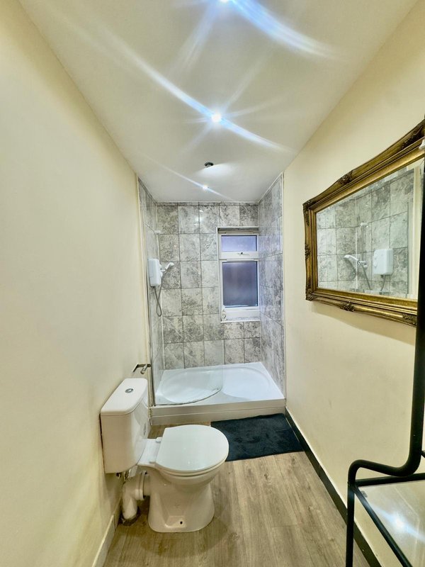 Bathroom with toilet, pedestal sink, shower enclosure and framed mirror on wall
