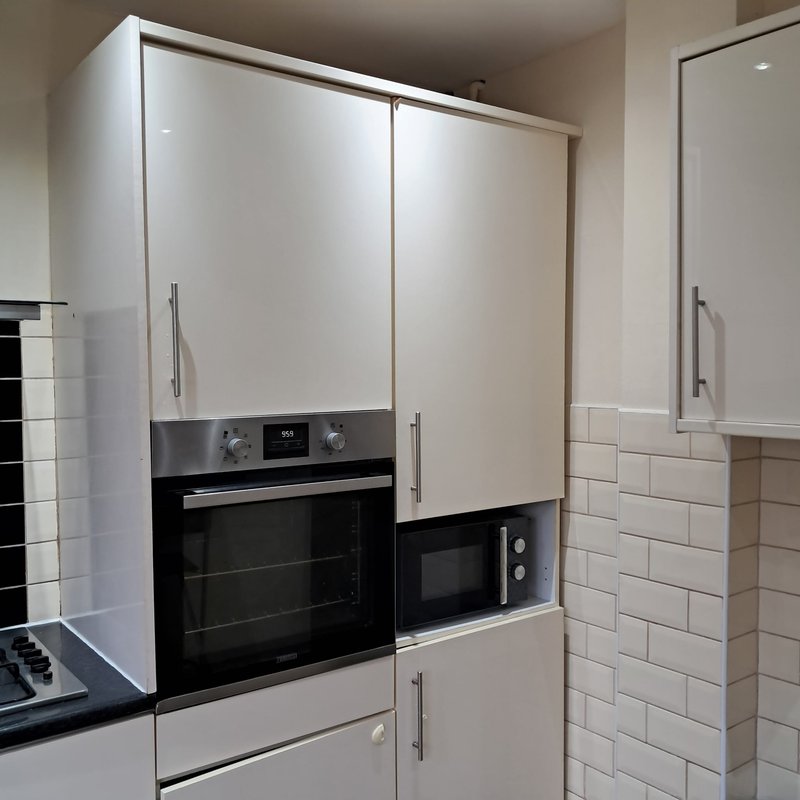 Modern kitchen with white cabinetry, built-in black oven and microwave appliances