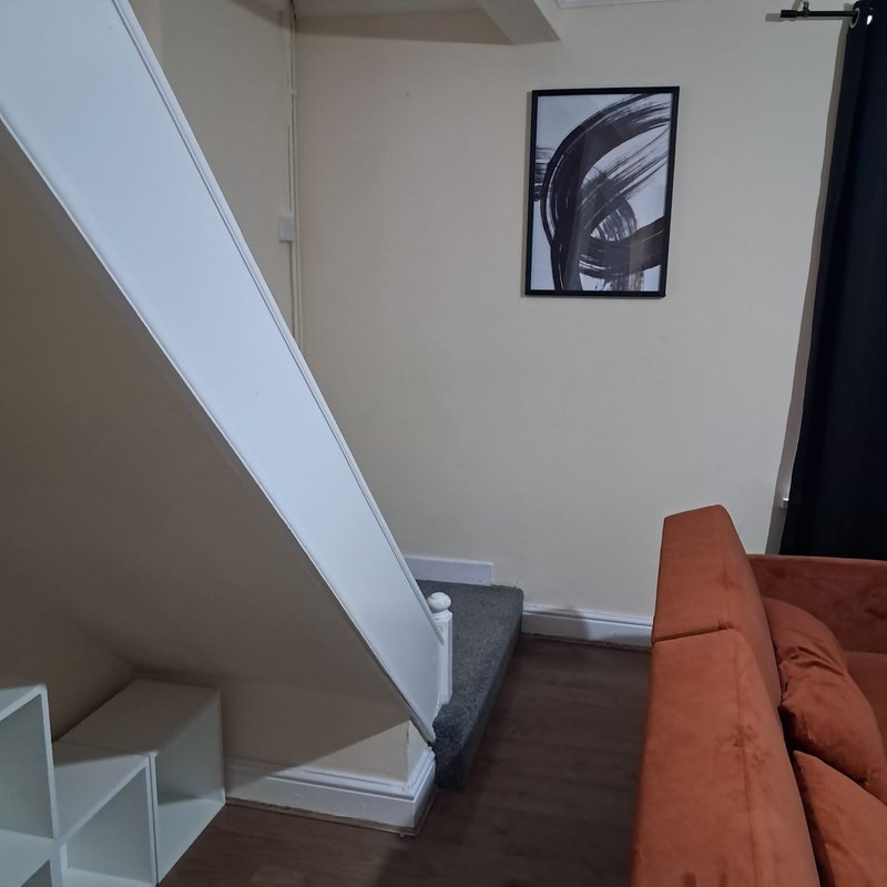 Staircase landing with orange sofa, framed wall art, and modern interior design