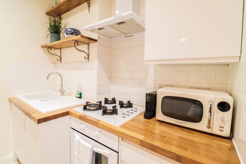 Compact kitchen with wooden countertops, white appliances, gas hob and cream microwave