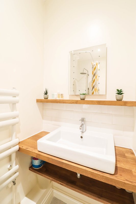 Modern bathroom with white sink, wooden vanity, mirror and wall-mounted shelving