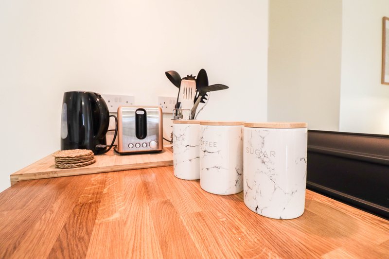 Kitchen counter with wooden surface, kettle, toaster, utensil holder and storage canisters