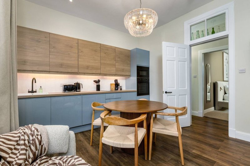 Open-plan kitchen and dining area with wooden table, mid-century chairs, and blue cabinetry