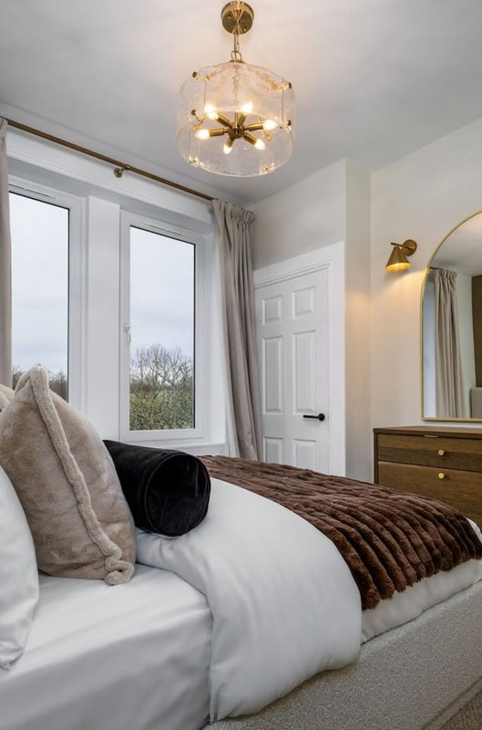 Modern bedroom with double bed, pendant light fixture, mirror, and garden view from windows
