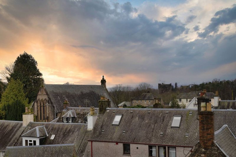 Rooftop view of residential neighbourhood with church, houses and trees at sunset