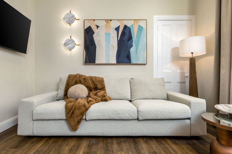 Modern living room with light grey sofa, throw blanket, decorative cushion and framed abstract artwork