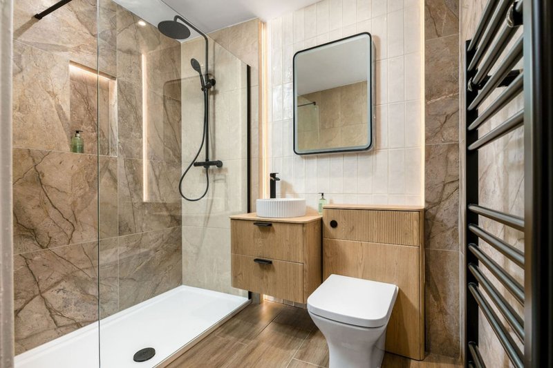 Modern bathroom with walk-in shower, wooden vanity, mirror and heated towel rail