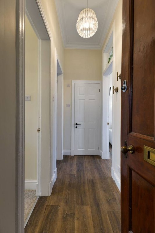 Hallway with white doors, wooden floor, pendant ceiling light and wall switches