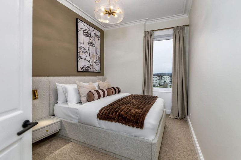Modern bedroom with double bed, striped cushions, framed wall art, and window with curtains