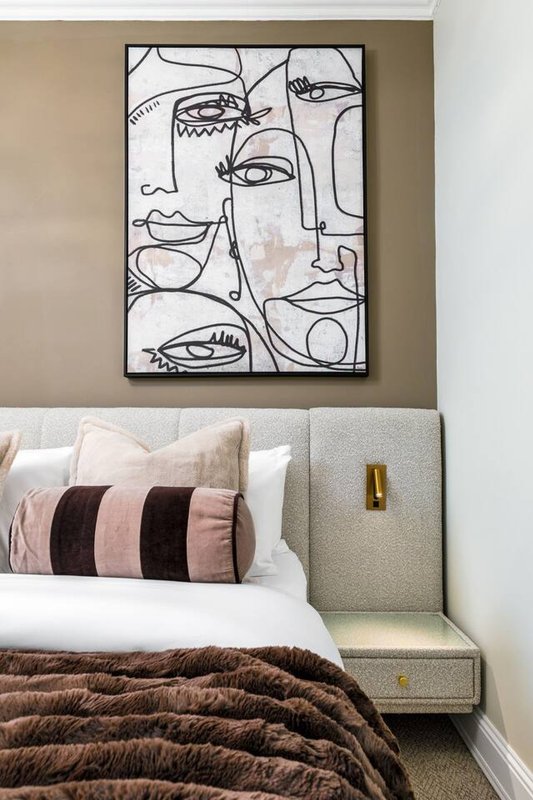Bedroom with double bed, striped cushions, abstract line art above headboard