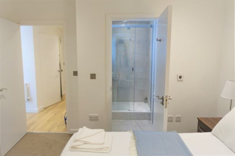 Modern bedroom with ensuite bathroom, double bed, wooden flooring and neutral decor